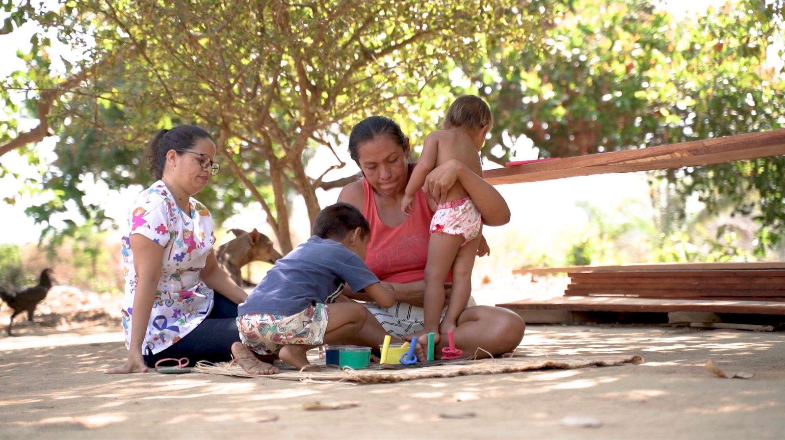 Família reunida à sombra de uma árvore, criança no colo