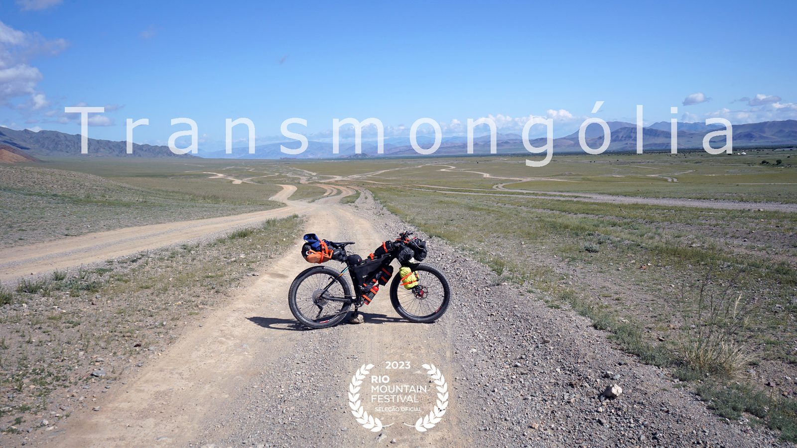 Bicicleta de bikepacking em estrada de terra na Mongólia, com selo do Rio Mountain Festival